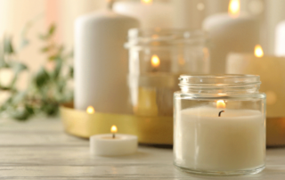 Candles burning on a table with foliage in the background