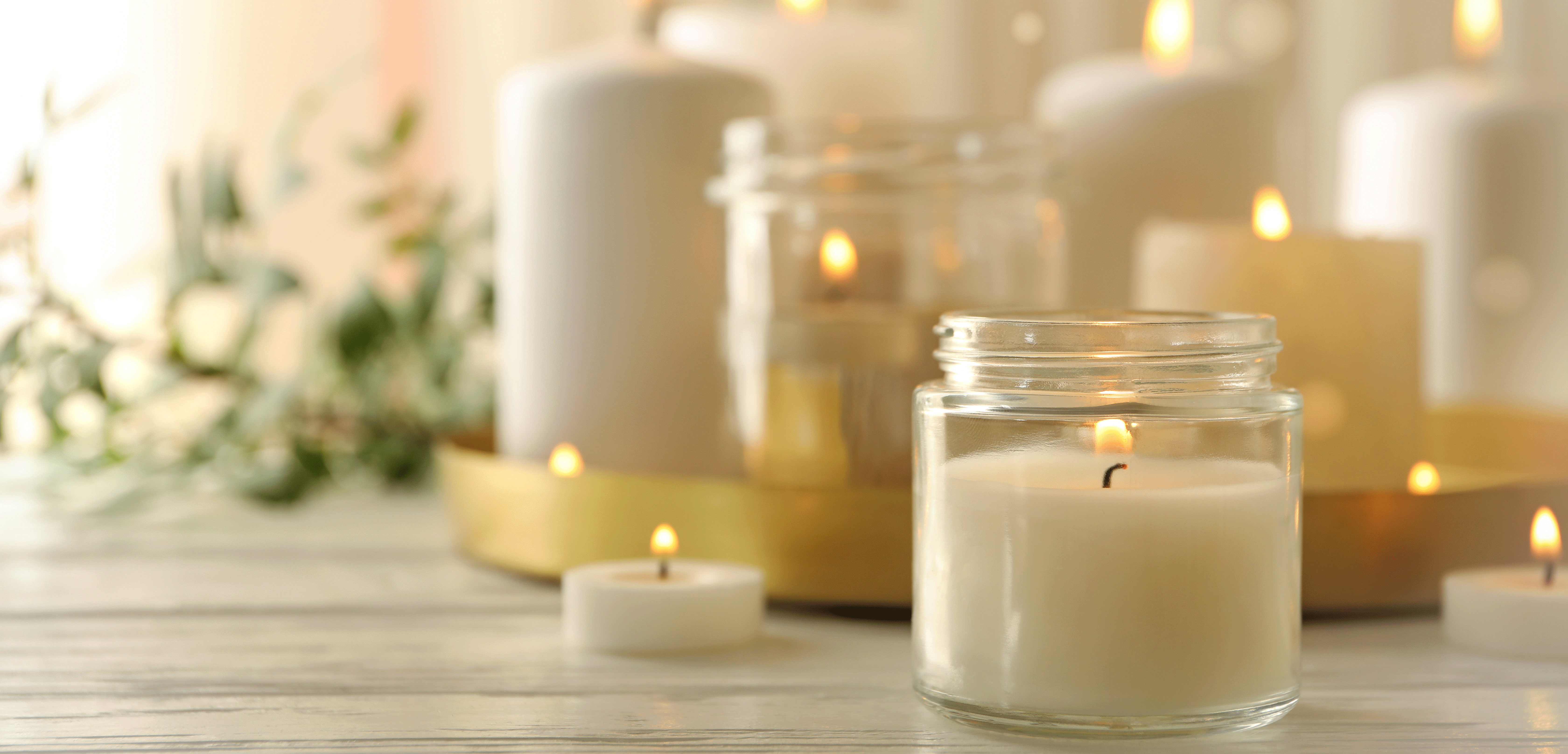 Candles burning on a table with foliage in the background